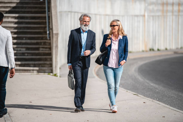 istock Two Business Workers Talking To Each Other While Walking On The Sidewalk 1435054632
