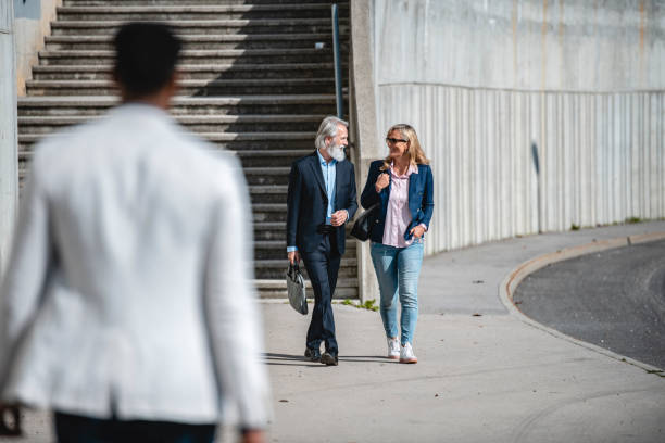 istock Two Mature Business Workers Talking To Each Other While Walking Together Outdoors 1435054637