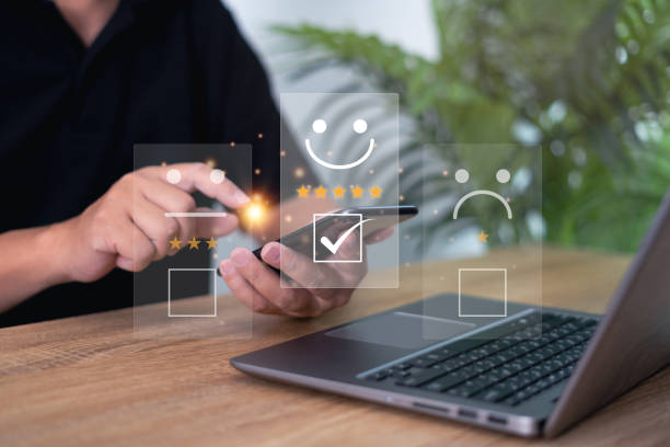 istock Customer satisfaction feedback survey and rating to service experience online application, Man people Satisfaction Rating on virtual screen the happy Smile icon with smartphone and laptop on table 1435058673