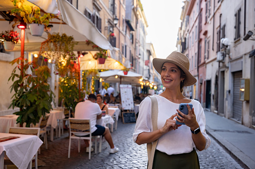 Happy female tourist walking around in Rome using a map on her cell phone - travel concepts