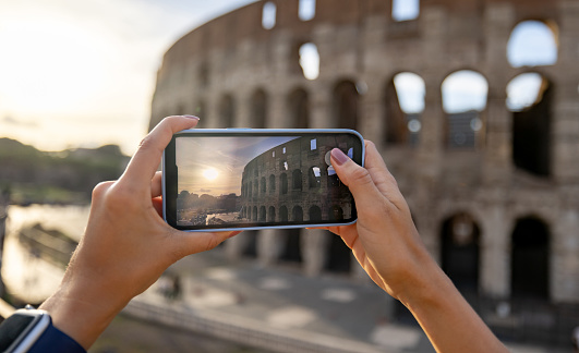 Close-up on a tourist photographing the Coliseum in Rome with her cell phone - traveling concepts