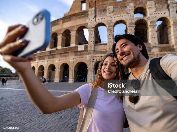 Happy Couple Of Travelers In Rome Taking A Selfie With The Coliseum Stock Photo - Download Image Now