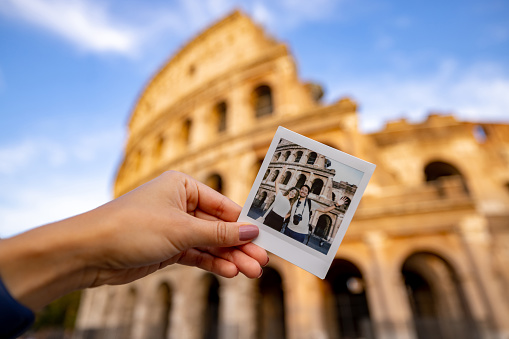 Happy couple of tourists in Rome taking a photo at the Coliseum with an instant camera â traveling concepts