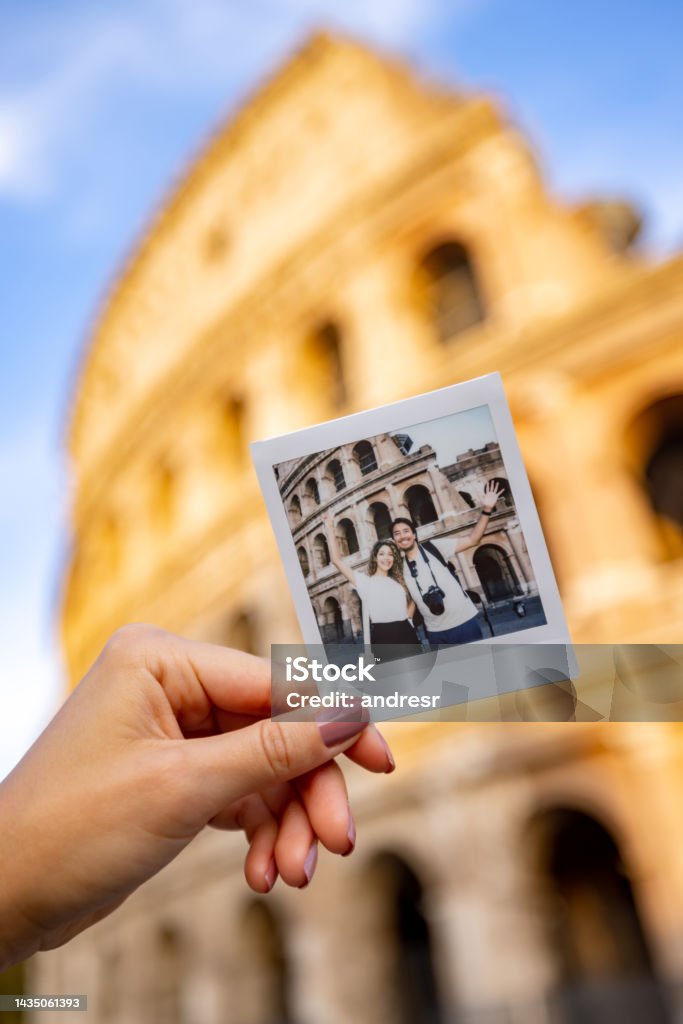 Tourists taking a photo at the Roman Coliseum with an instant camera Happy couple of tourists taking a photo at the Roman Coliseum with an instant camera - traveling concepts Rome - Italy Stock Photo