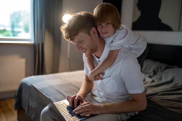 istock Father and son lying in bed and spending time on internet 1435061839