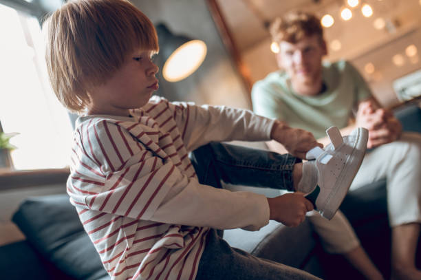 istock Little boy looking busy while getting on his shoes 1435061905