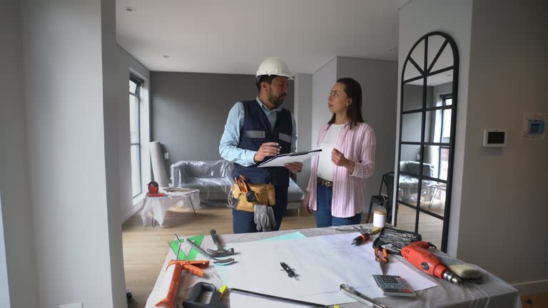 Male contractor showing his plan to female customer at a home renovation project