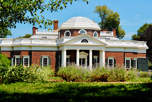 Charlottesville, Virginia, USA - June 17, 2012: Plants and trees frame Thomas Jefferson’s home, Monticello, on a bright sunny day.