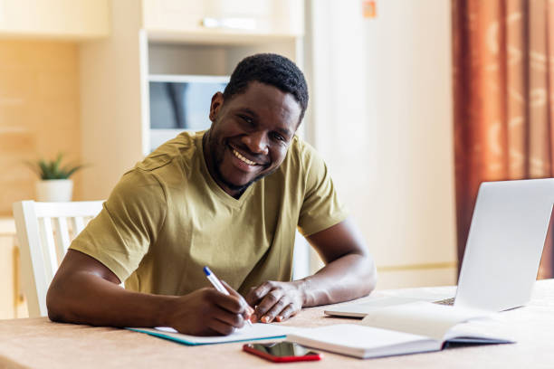 istock latin hispanic man looking happy while sitting with laptop and papers at kitchen 1435069370