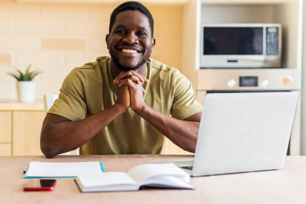 istock latin hispanic man looking happy while sitting with laptop and papers at kitchen 1435069387