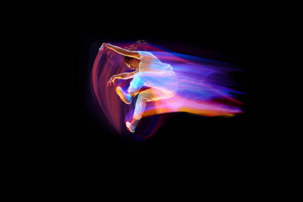 istock In miracle flight. Young sportive dancer in white clothes levitating, moving over dark background in mixed neon light. Creative art, aspiration, music, fashion, dance 1435069756