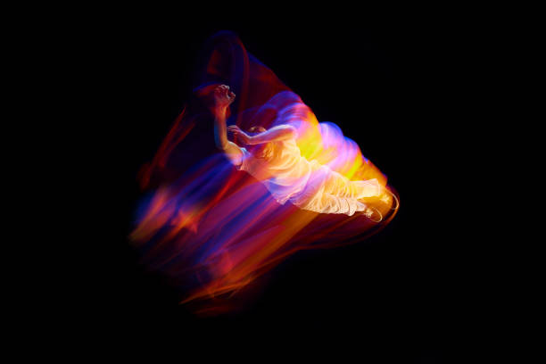 Dance in motion. Studio shot of flying, jumping dancer or gymnast performing tricks in the air over black background with mixed neon glowing rays Dance in motion. Studio shot of flying, jumping dancer or gymnast performing tricks in the air over black background with mixed neon glowing rays. Fantasy, cyberpunk, sport, fashion hyperdrive stock pictures, royalty-free photos & images