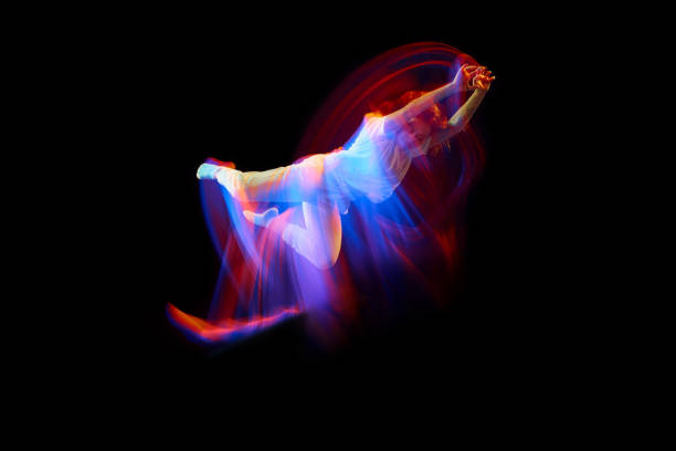 istock In miracle flight. Young sportive dancer in white clothes levitating, moving over dark background in mixed neon light. Creative art, aspiration, music, fashion, dance 1435069820