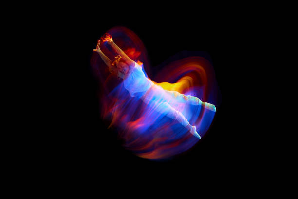 Levitation. One flying, jumping dancer or gymnast performing tricks in the air over black background with mixed neon glowing rays Levitation. One flying, jumping dancer or gymnast performing tricks in the air over black background with mixed neon glowing rays. Fantasy, cyberpunk, sport, fashion hyperdrive stock pictures, royalty-free photos & images