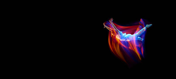 Levitation. One flying, jumping dancer or gymnast performing tricks in the air over black background with mixed neon glowing rays Levitation. One flying, jumping dancer or gymnast performing tricks in the air over black background with mixed neon glowing rays. Fantasy, cyberpunk, sport, fashion hyperdrive stock pictures, royalty-free photos & images