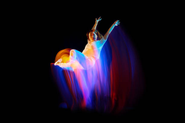 istock In miracle flight. Young sportive dancer in white clothes levitating, moving over dark background in mixed neon light. Creative art, aspiration, music, fashion, dance 1435069852