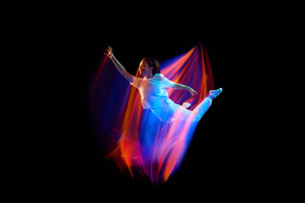 istock In miracle flight. Young sportive dancer in white clothes levitating, moving over dark background in mixed neon light. Creative art, aspiration, music, fashion, dance 1435069858