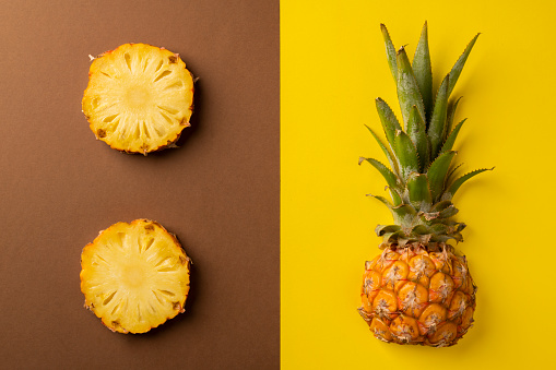 Ripe pineapple cut and lying on a bicolor background. Decorative composition and top view.