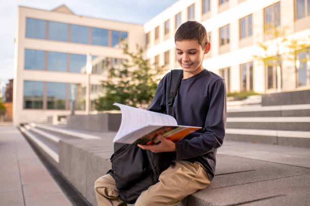 istock Pleased adolescent flipping through a textbook in his hands 1435071782