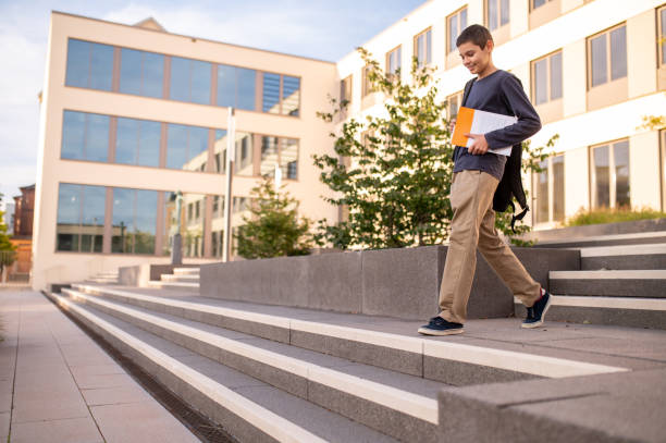adolescente com um livro descendo os degraus de concreto ao ar livre - staircase steps moving down student - fotografias e filmes do acervo