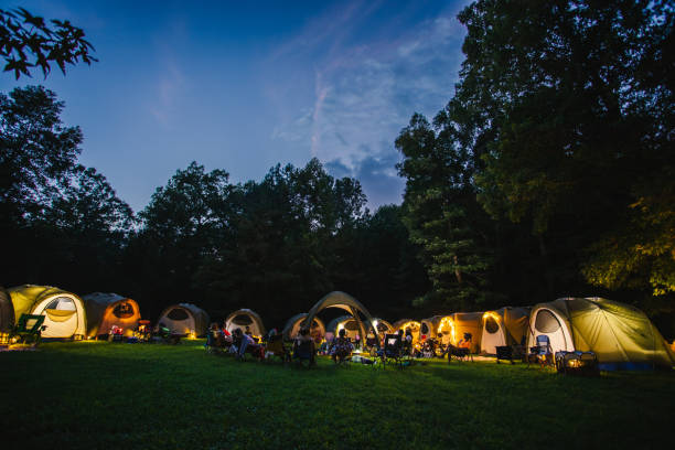 large group of tents illuminated as the night falls over camp