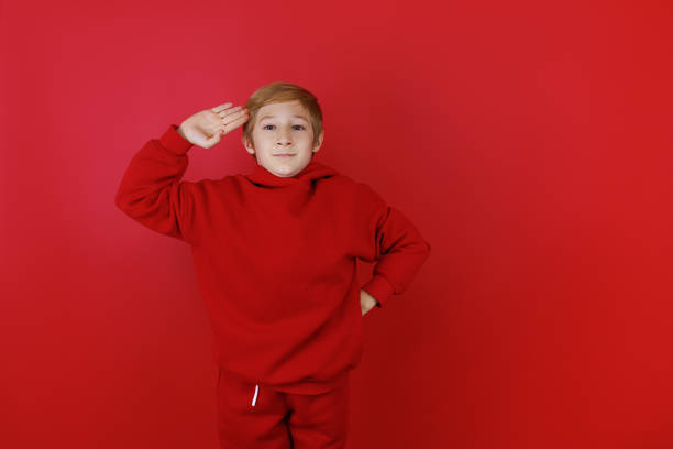 istock cheerful boy in a red tracksuit gesturing on a red background 1435074423