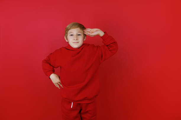 istock cheerful boy in a red tracksuit gesturing on a red background 1435074427