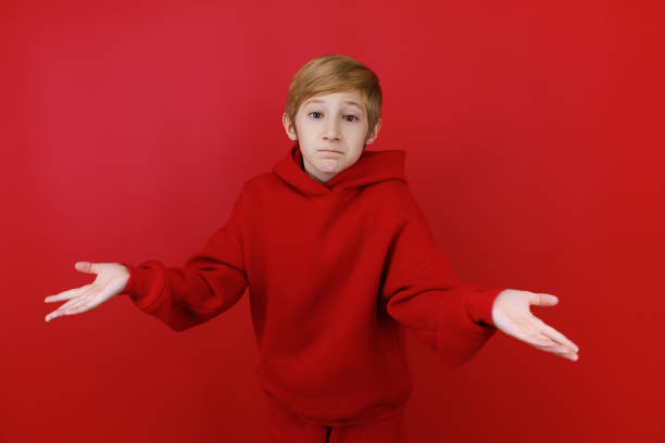 istock cheerful boy in a red tracksuit gesturing on a red background 1435074466