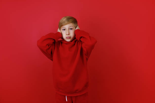 istock cheerful boy in a red tracksuit gesturing on a red background 1435074480