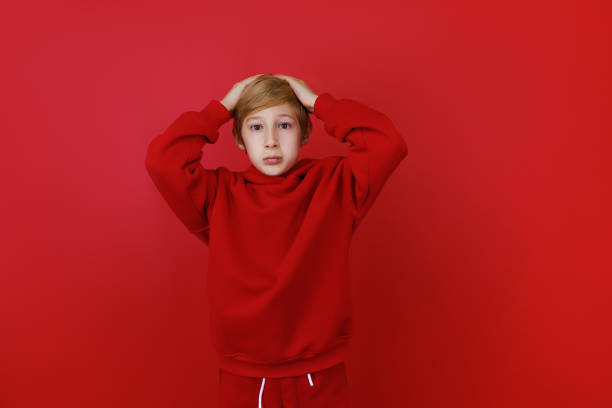 istock cheerful boy in a red tracksuit gesturing on a red background 1435074483