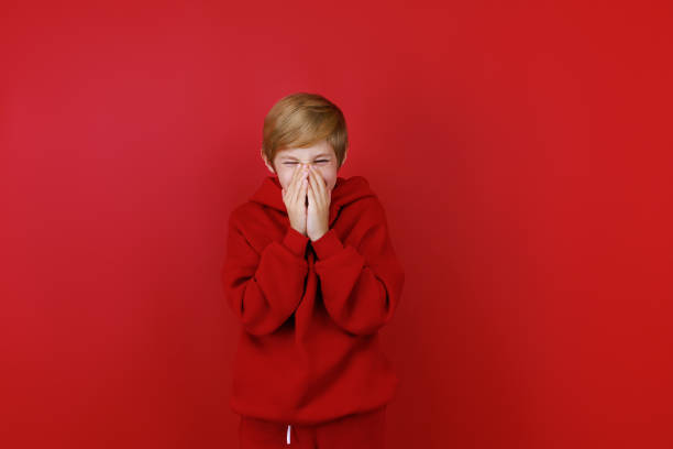 istock cheerful boy in a red tracksuit gesturing on a red background 1435074537