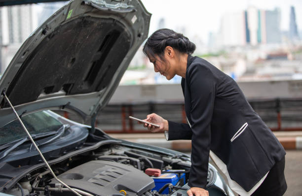 A businesswoman is calling for help as her car breaks down on the side of the road. stock photo