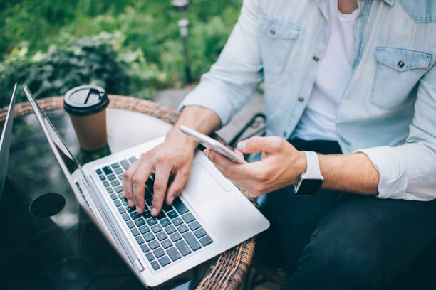 istock Man using laptop and smartphone outside cafe 1435077053