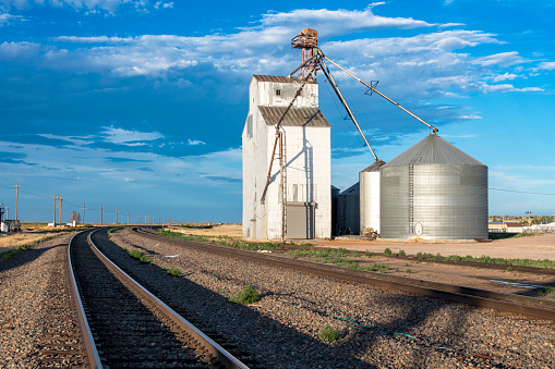 A grain silo along the railroad tracks. It is located on a siding connected to the Union Pacific main line. The image captures a scene repeated thousands of times across the American heartland depicting a rural grain transloading site.\nPine Bluffs, Wyoming, USA\n07/08/2022
