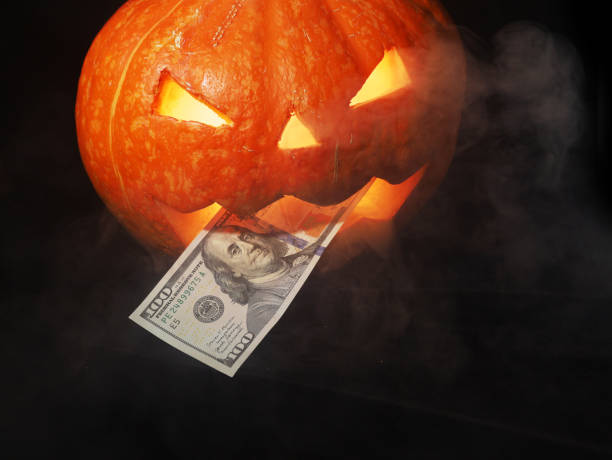 istock Halloween pumpkin and dollars on black background. 1435078117