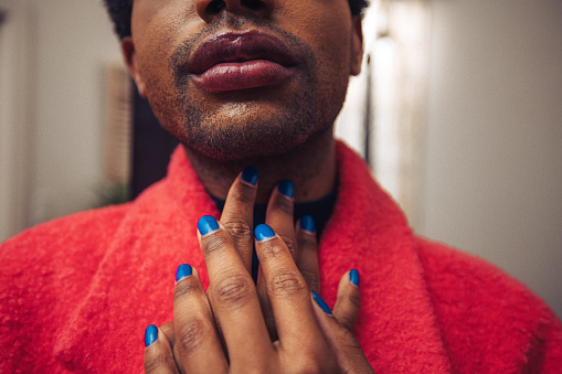Non-binary person with polished nails getting dressed with a pink jacket. Close up shot on hands.