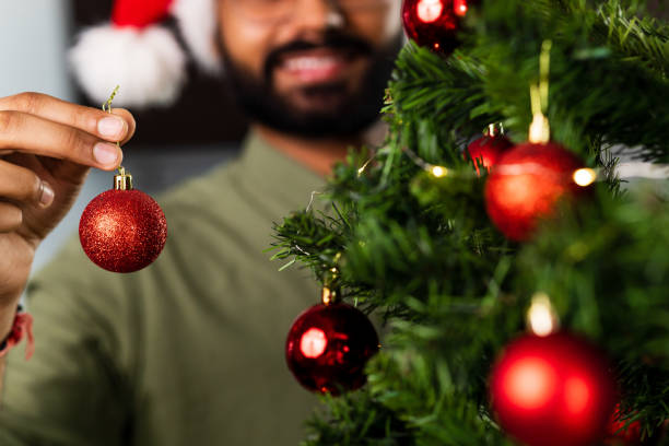 istock indian man in santa hat decorating Christmas tree with baubles 1435081814