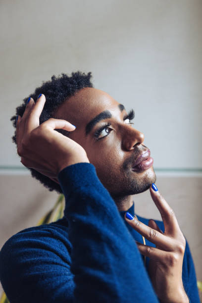 Home portrait of a Non-Binary person Home portrait of a Non-Binary person posing next to a window. bi black stock pictures, royalty-free photos & images