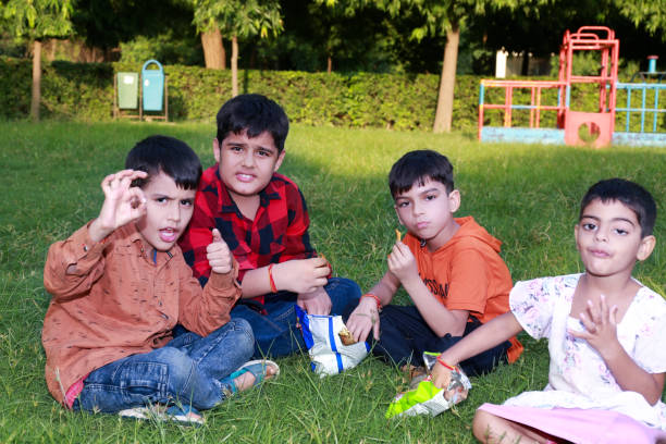 istock Elementary children eating potato chips portrait in the park 1435084008