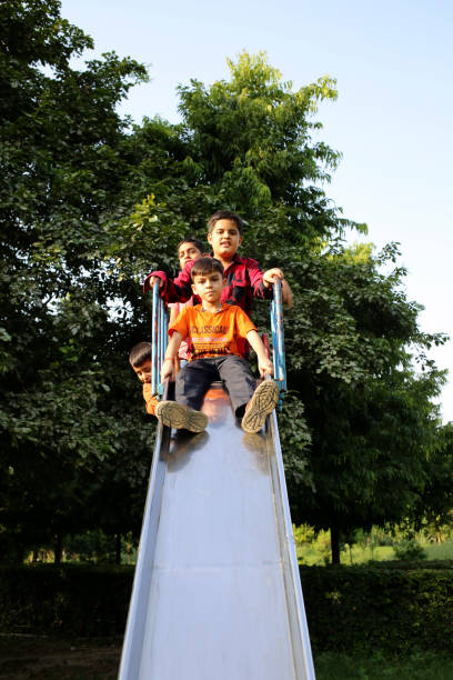 Elementary age school children of Indian ethnicity having fun on the slide in the park