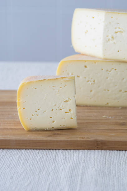 istock Cutted round partmesan or pecorino cheese head on wooden board on light background. Fresh dairy product, healthy organic food, selective focus, copyspace. Delicious appetizer. 1435085549