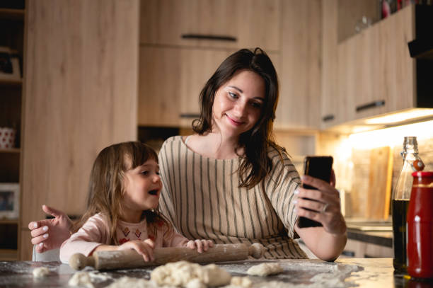 istock young woman taking selfie with her daughter while cooking at home in a kitchen. 1435085700