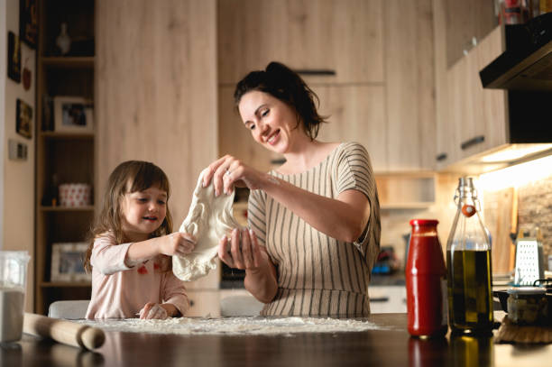 mujer con niño preparando masa para pizza casera. madre e hijos cocinando pizza en la cocina. - makes the dough fotografías e imágenes de stock