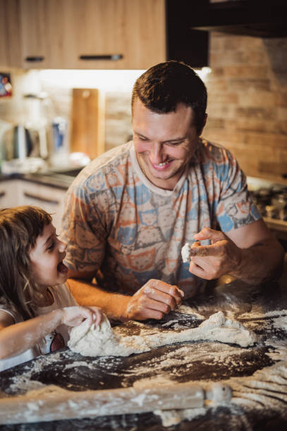 istock father and daughter making dough while preparing pastry in kitchen together. authentic real family.  father with a small daughter cooking together the dough for pies. 1435086859