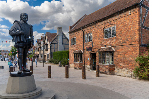 Stratford-Upon-Avon, United Kingdom - 31 August, 2022: statue of William Shakespeare and view of downtown Stratford