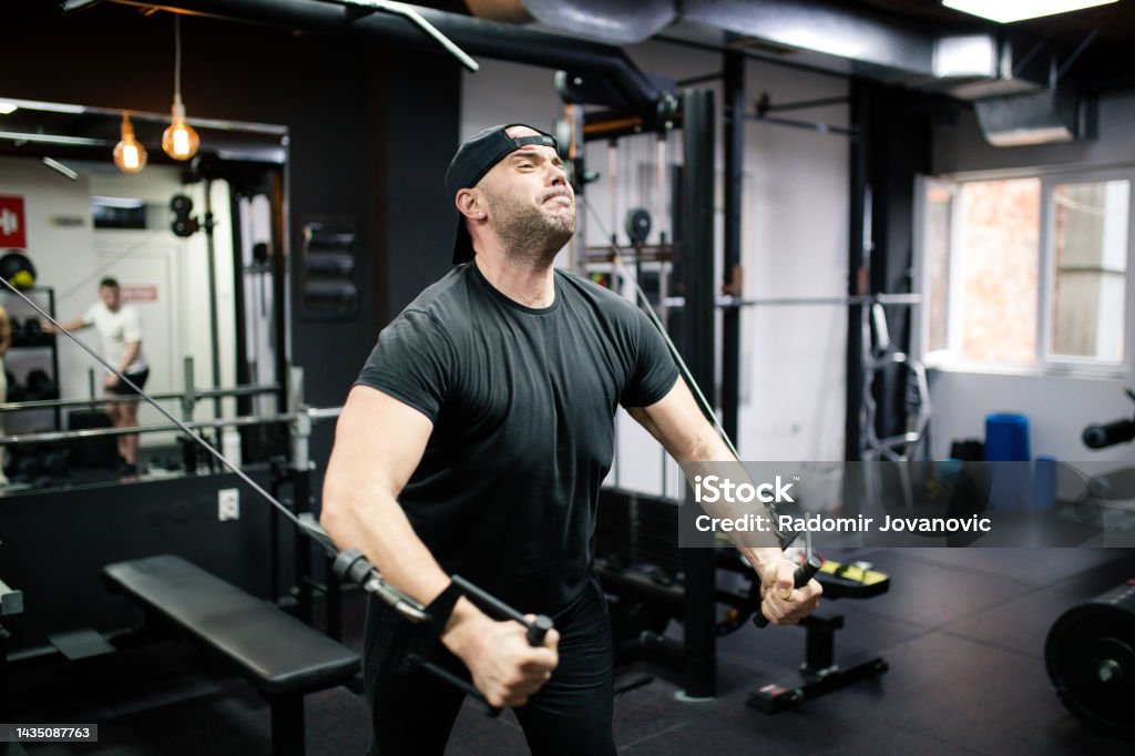 Man working out in crossover gym machine Muscular man working out at bodybuilding gym 30-34 Years Stock Photo