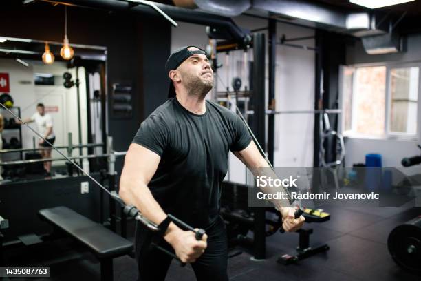 Man Working Out In Crossover Gym Machine Stock Photo - Download Image Now - 30-34 Years, Abdominal Muscle, Active Lifestyle