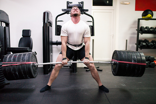 Caucasian muscular man doing deadlifts in the gym