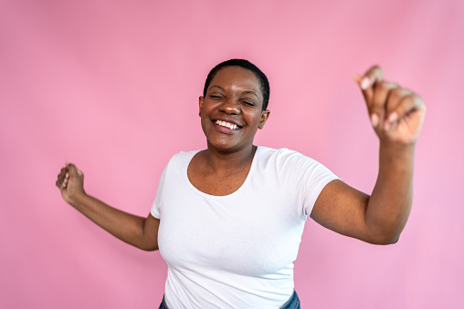 Happy mature woman dancing with a pink background
