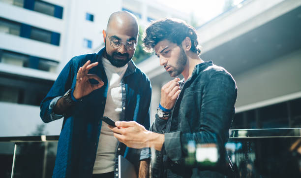 istock Middle Eastern male employees reading received email message with job task discussing business opportunity outdoors, Turkish entrepreneurs using modern cellular technology for booking and banking 1435089805